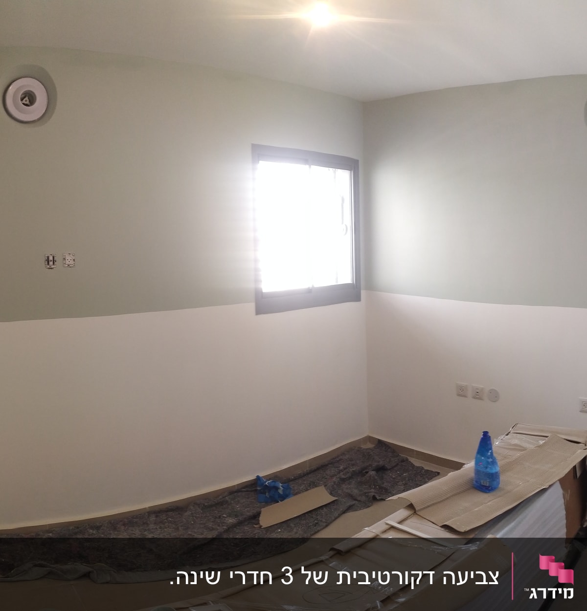 חדר צבוע בשני גוונים עם ציוד צביעה על הרצפה